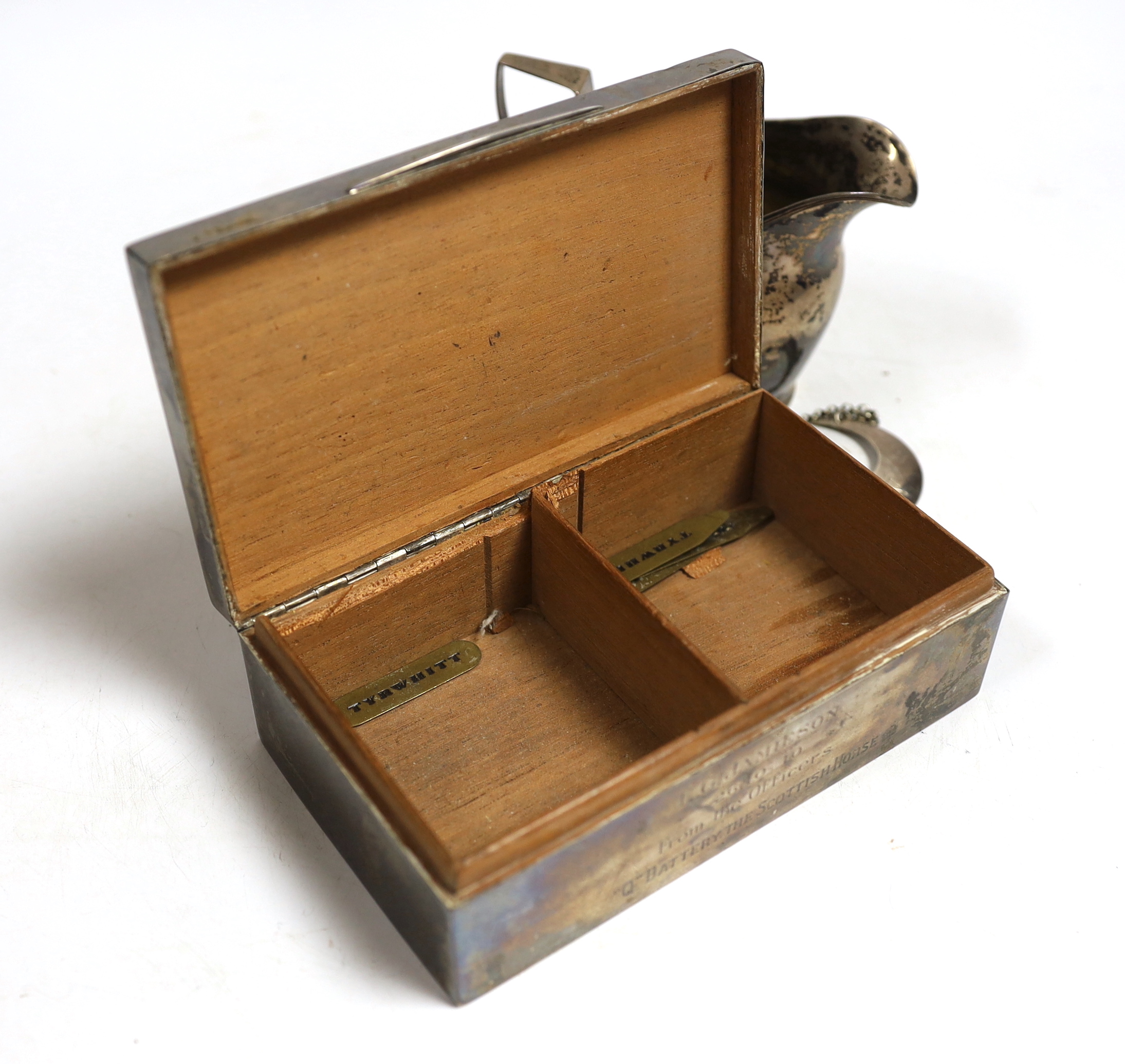 A George V Art Deco silver mounted rectangular cigarette box, with engraved inscription, Birmingham, 1932, 15.1cm, a Georgian silver cream jug, maker possibly William Welch II of Exeter? and a Georgian silver crescent 'G